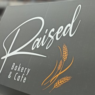 Painted “Raised” script with orange wheat (detail, prev.employer)