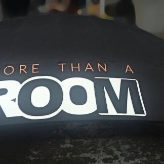 Process — applying the white/black “ROOM” logo and orange “MORE THAN A” letters on the curved sign band (prev. employer)